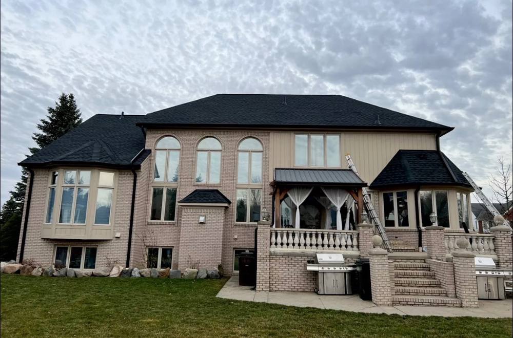 Large brick home rear elevation with black gutters and metal accent roof