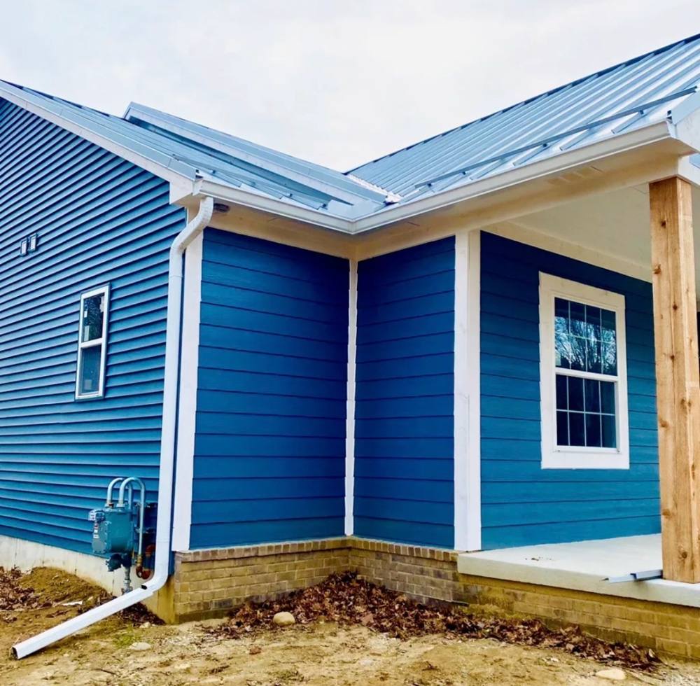 Blue home corner with clean white gutter and downspout installation